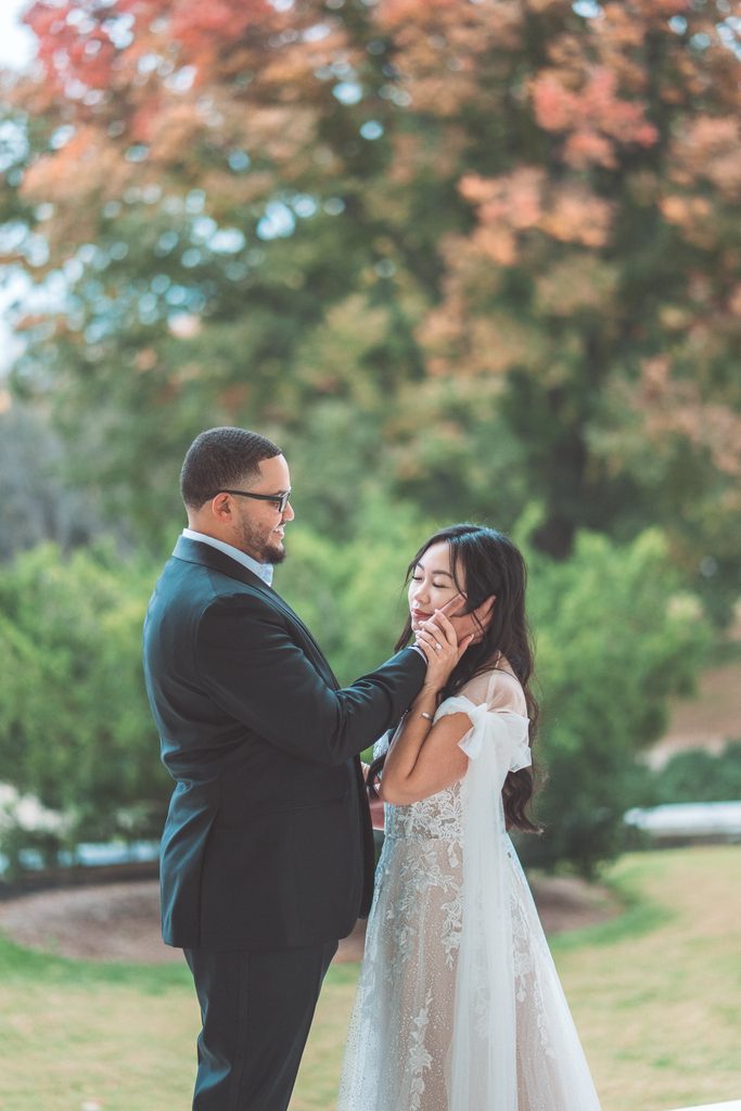 Couple sharing a quiet moment outdoors with the man gently holding his fiancée’s face.