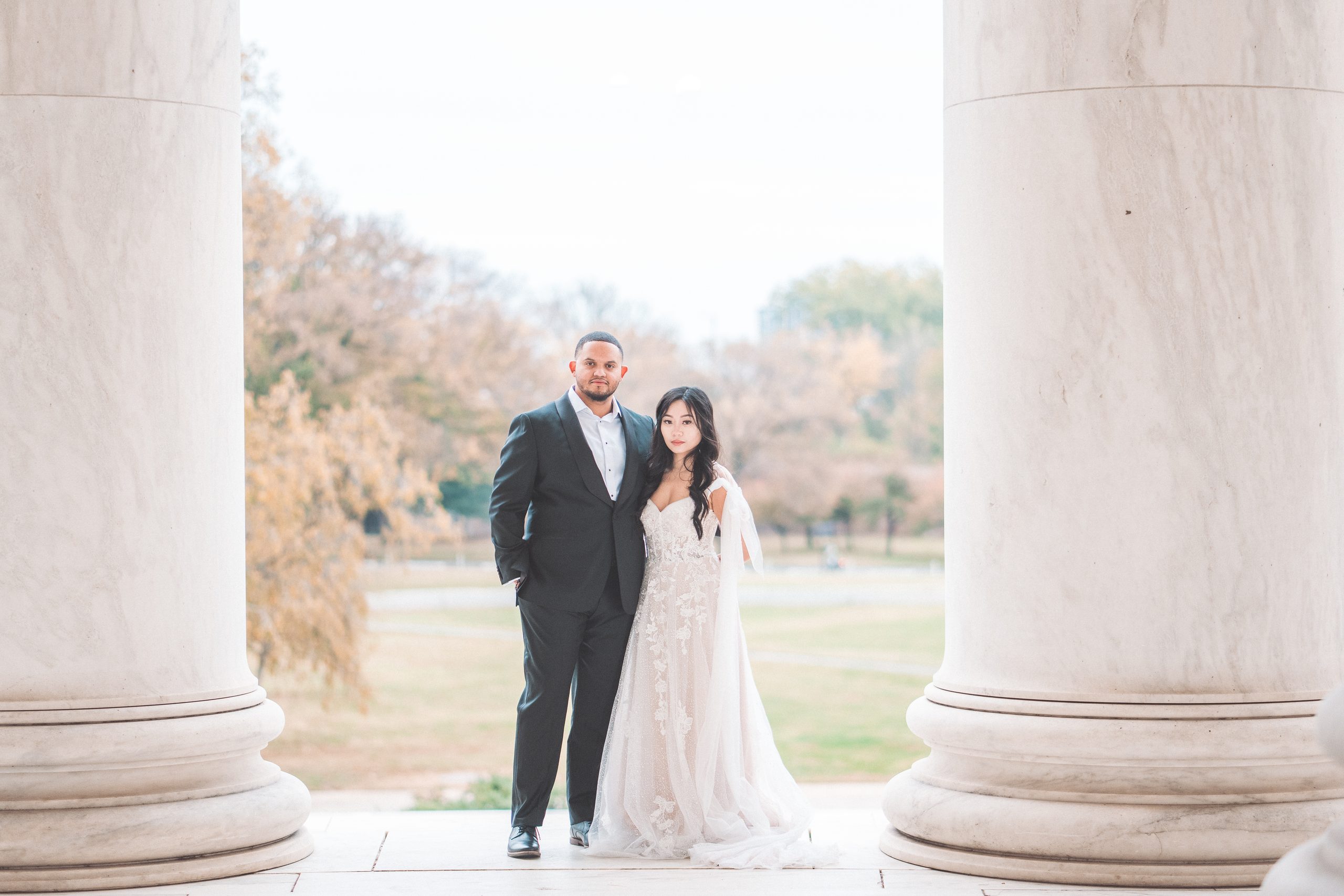 Couple posing together between the marble columns during their Jefferson Memorial engagement photos.