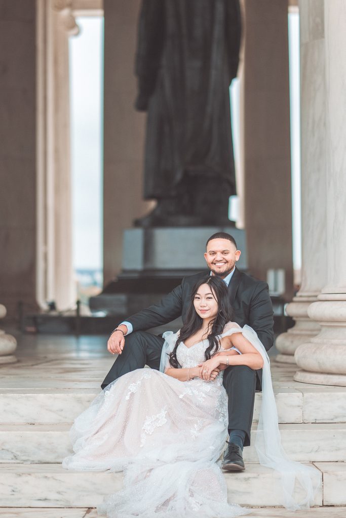 Engaged couple sitting together on the marble steps inside the Jefferson Memorial.