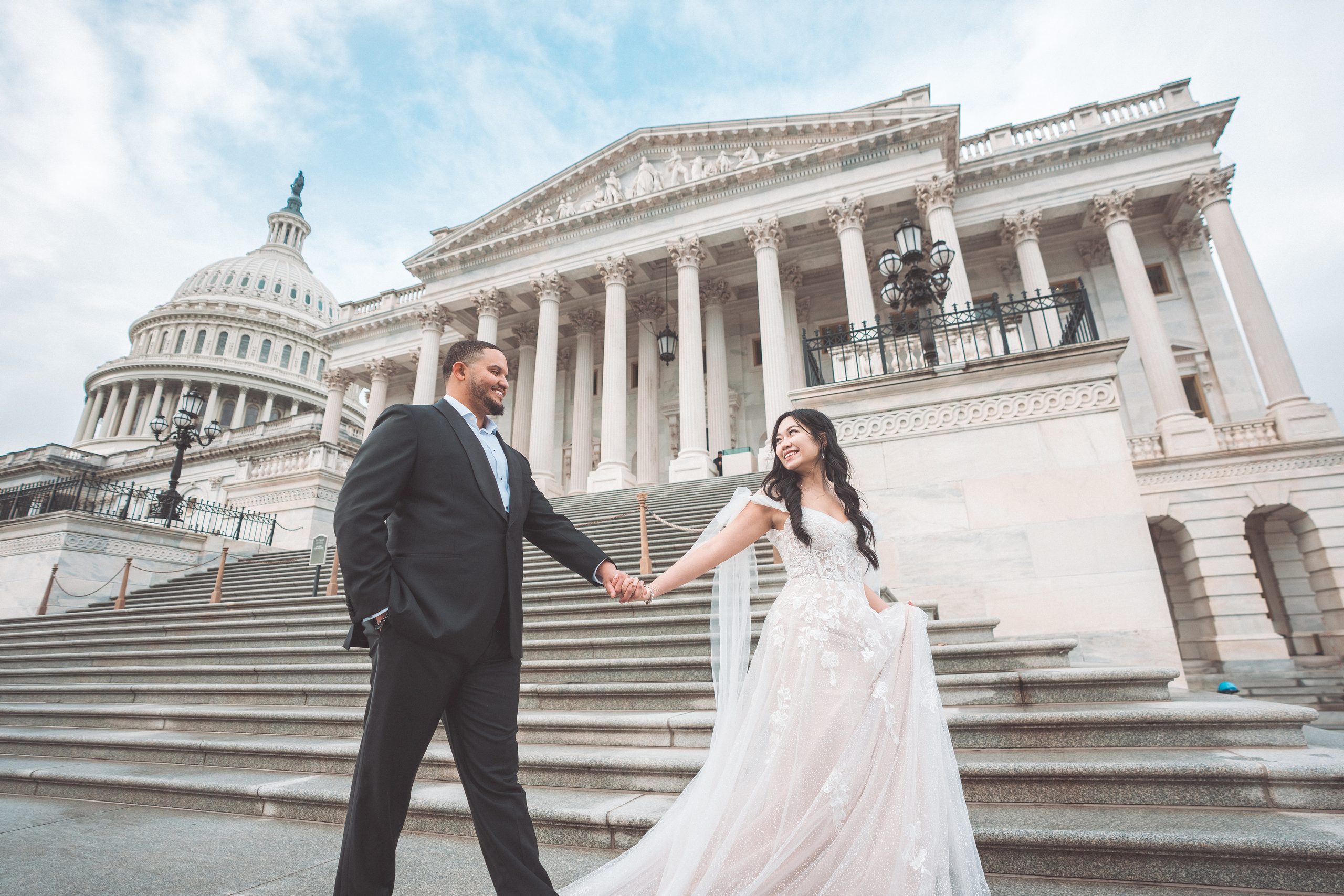 Couple holding hands and smiling at each other on the steps of the U.S. Capitol in Washington DC.