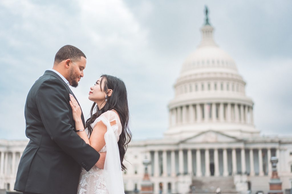 Romantic engagement portrait of a couple embracing with the U.S. Capitol building in the background.