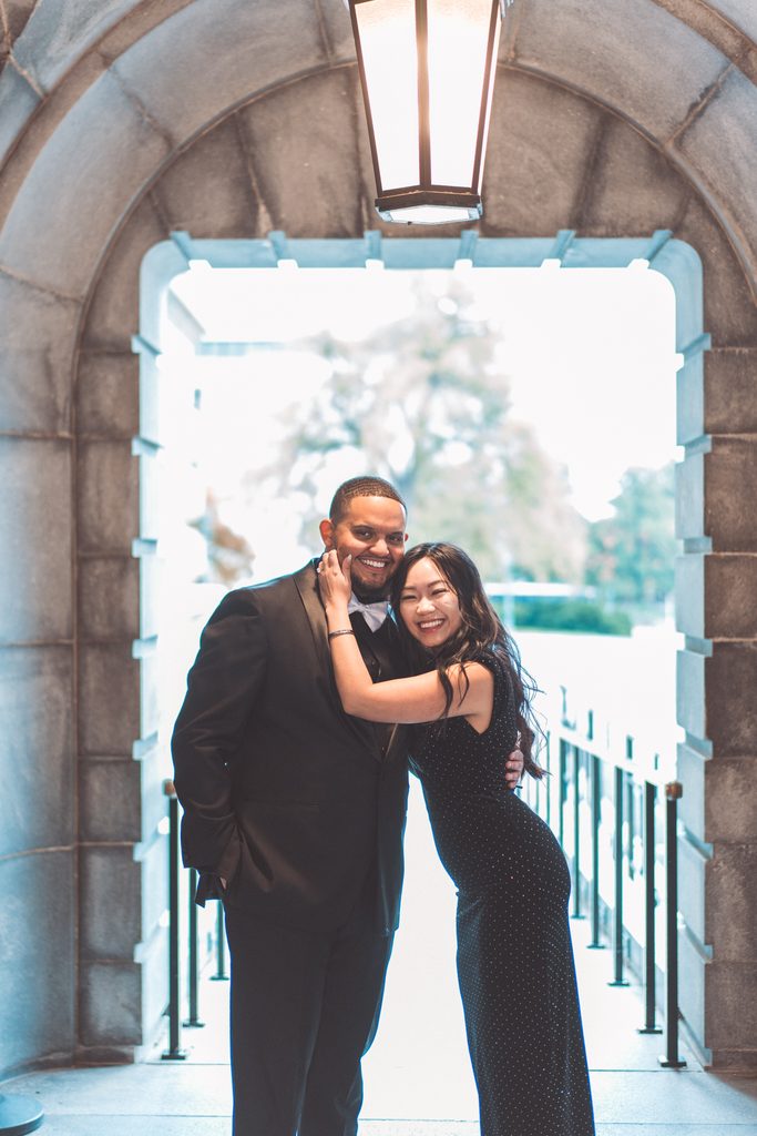 Couple smiling and embracing together beneath a stone archway in Washington DC.