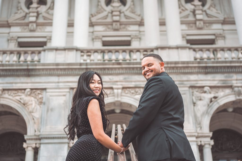 Engaged couple turning back toward the camera in front of historic DC architecture during their Jefferson Memorial engagement photos.