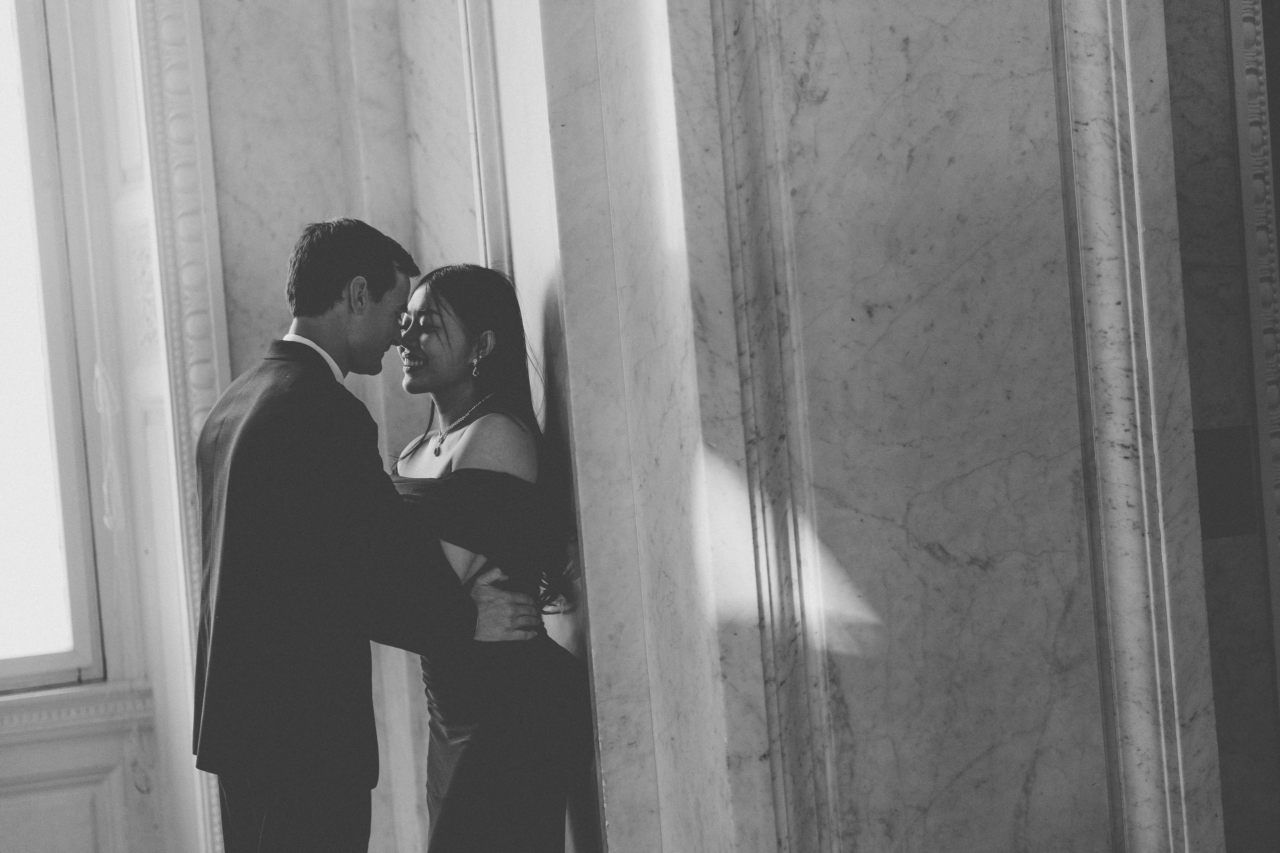 Black and white intimate portrait of a couple smiling together beside the marble columns.