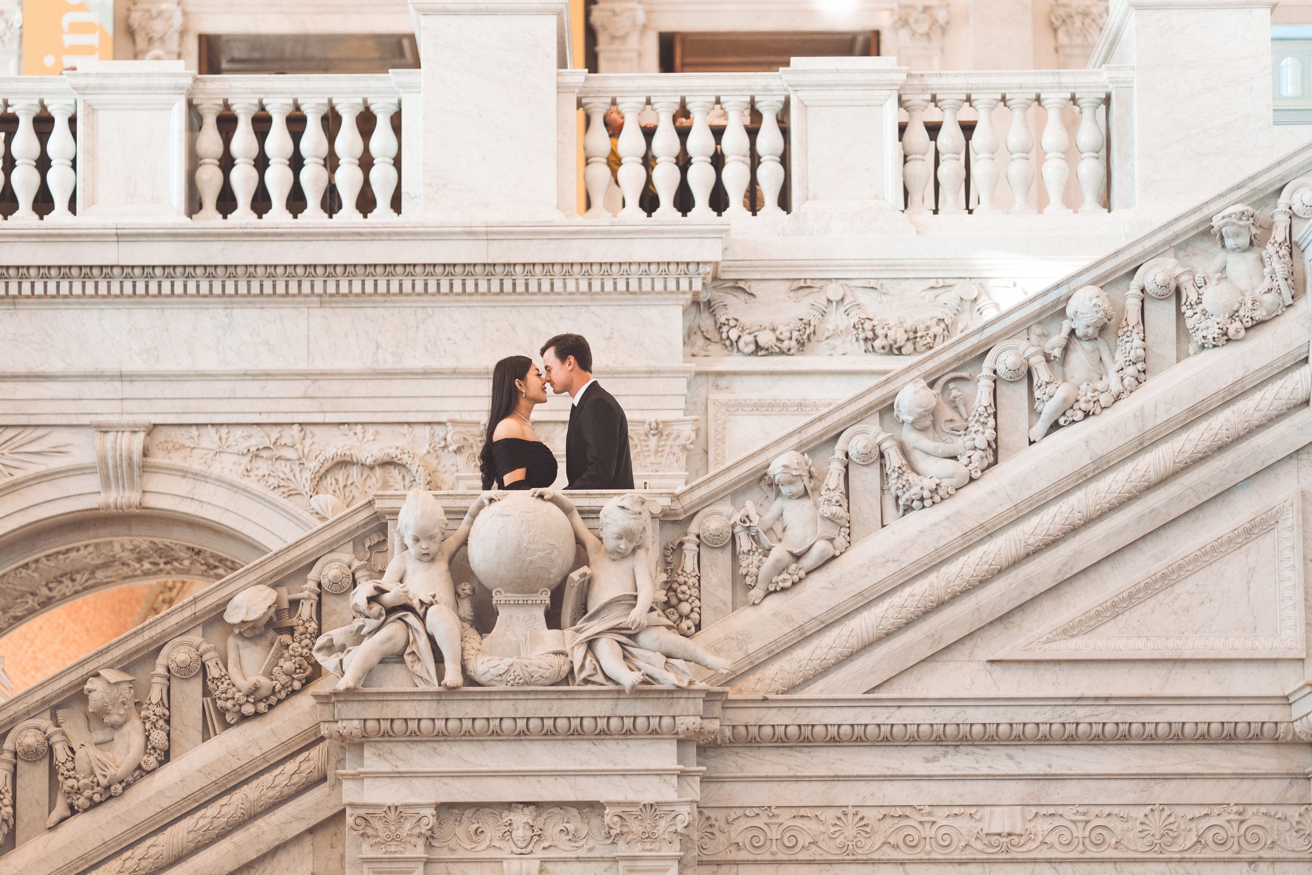 Couple sharing a quiet moment above the ornate marble staircase during their Library of Congress Engagement Photos.