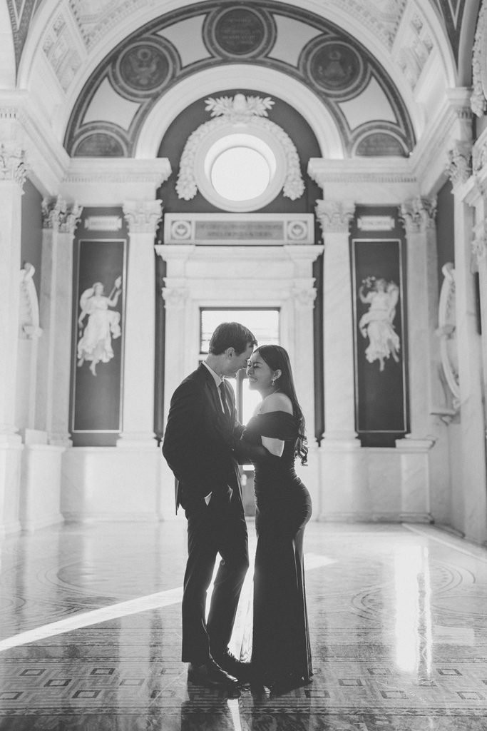 Black and white Library of Congress Engagement Photos of a couple sharing an intimate moment beneath the ornate arches and artwork.