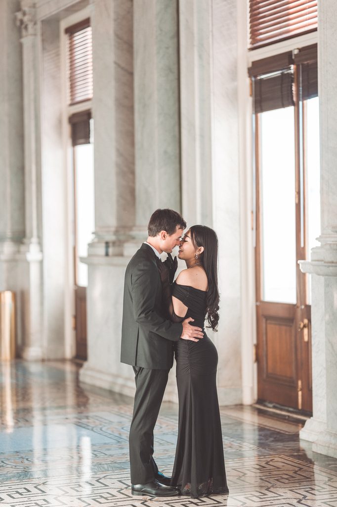Couple standing close together among the marble columns during their Library of Congress Engagement Photos.