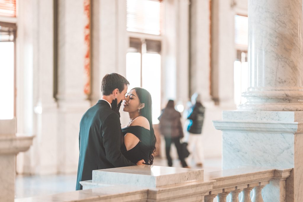 Romantic engagement portrait of a couple leaning in for a kiss inside the Library of Congress.