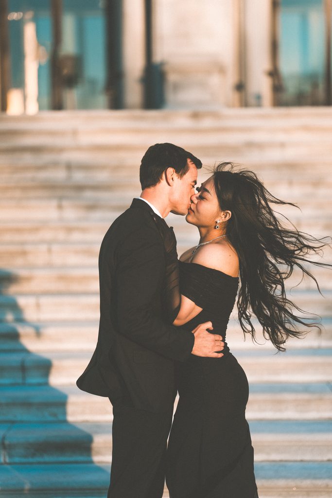 Couple kissing outdoors with wind blowing through her hair during their Washington DC engagement session.