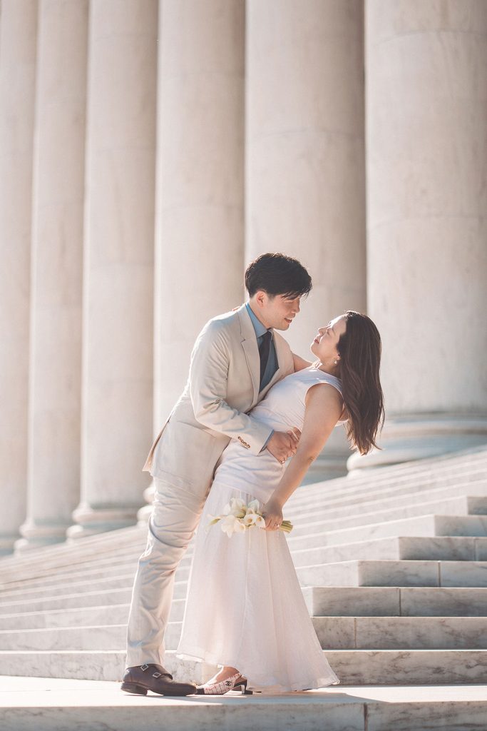 National Gallery of Art engagement photos of a couple sharing a playful dip on the exterior marble steps and columns.