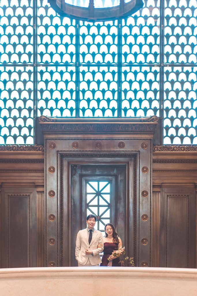National Gallery of Art engagement photos of a couple framed by ornate architecture and a patterned glass ceiling.