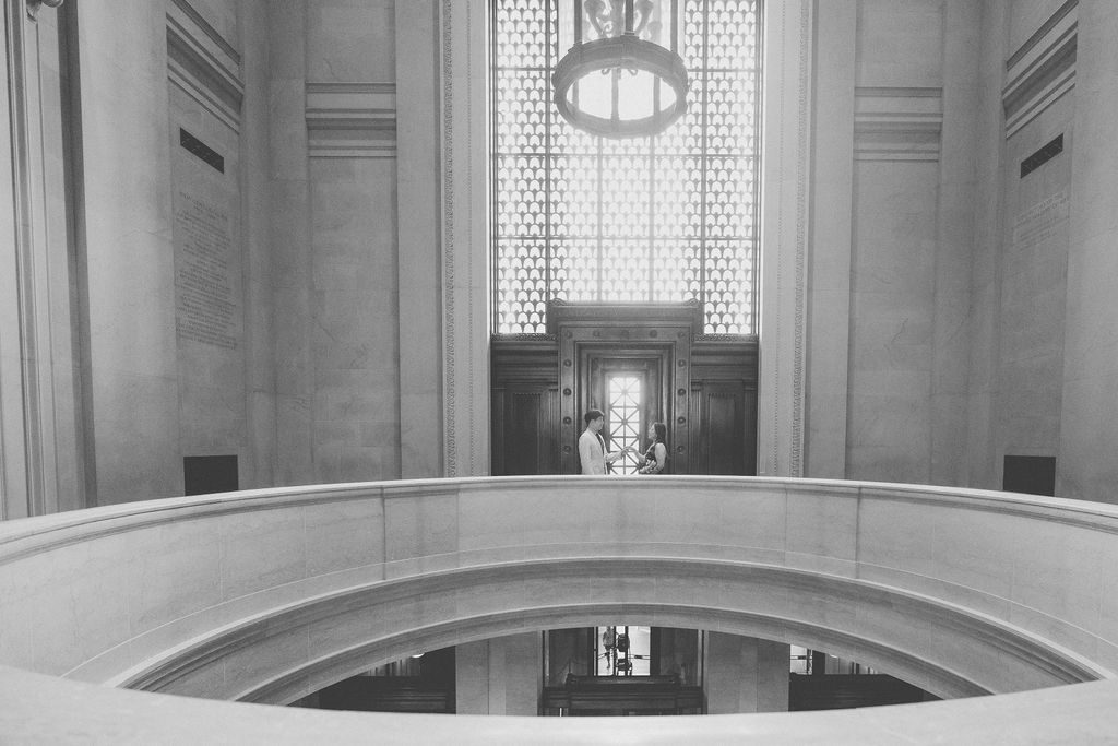 National Gallery of Art engagement photos of a couple standing beneath a grand window and architectural details inside the museum.
