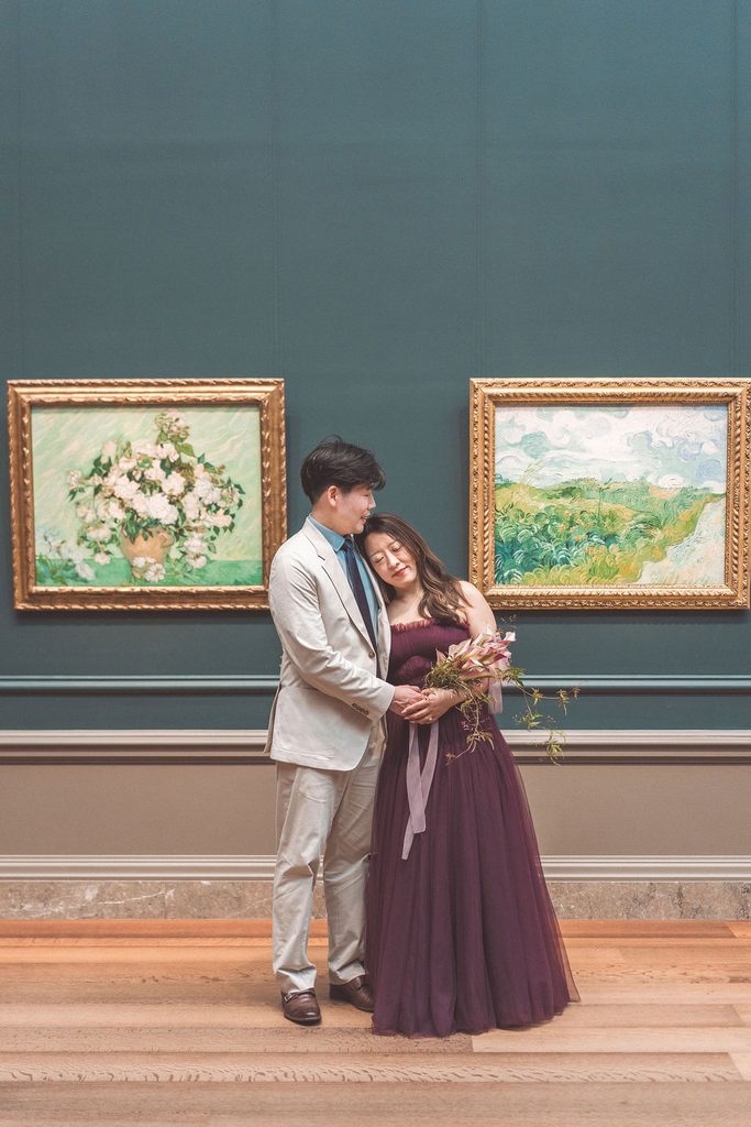 National Gallery of Art engagement photos of a couple embracing beneath two colorful paintings in a museum gallery.