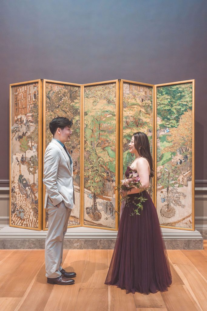 National Gallery of Art engagement photos of a couple facing each other in front of a colorful decorative art screen.