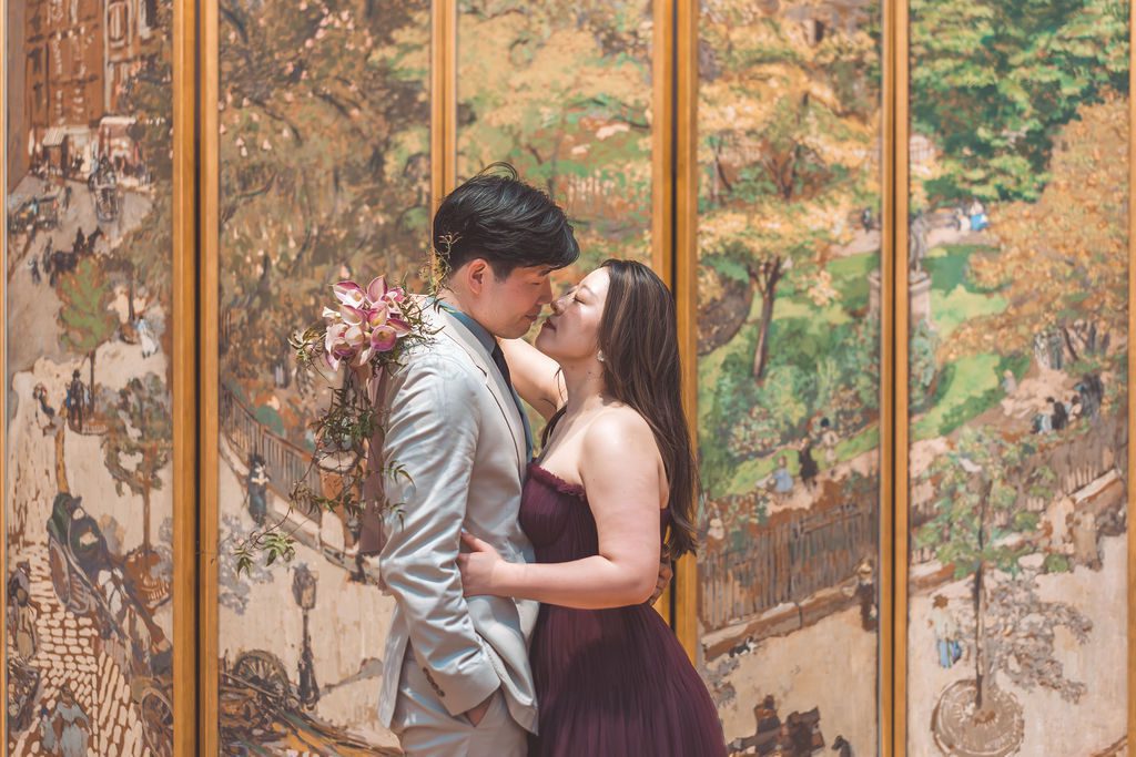 National Gallery of Art engagement photos of a couple kissing in front of a colorful decorative art screen while holding a floral bouquet.